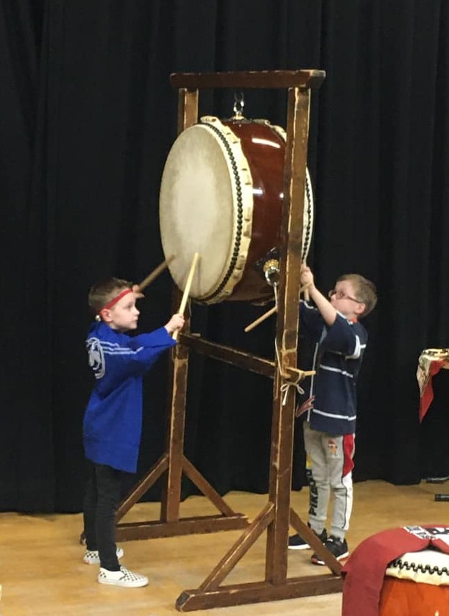 Two children using large Japanese drums